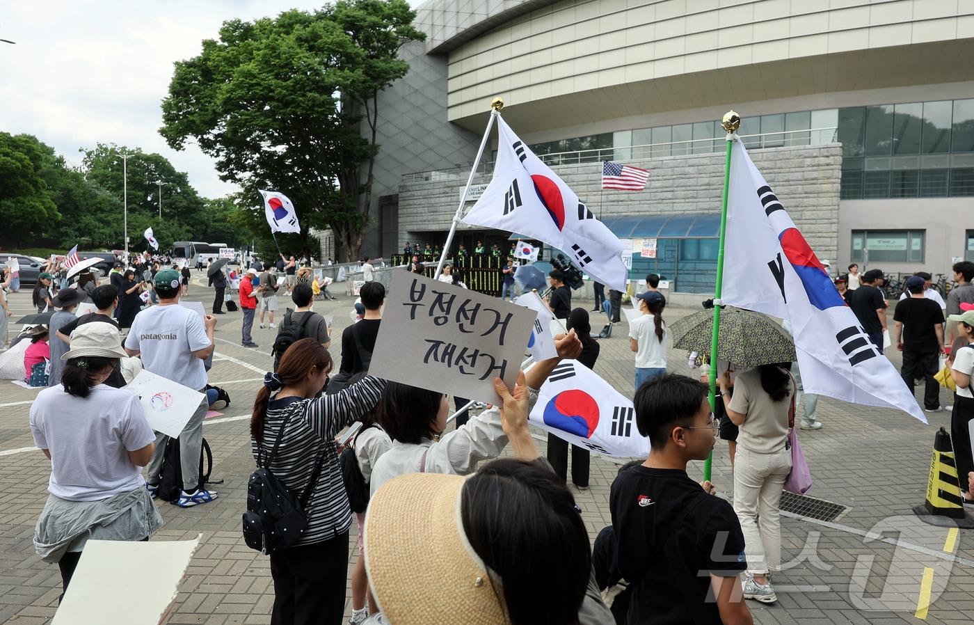 본문 이미지 - 제9회 전국동시지방선거 투표용지 부족 사태에 반발한 시민들이 8일 서울 송파구 올림픽공원 핸드볼경기장 개표소 앞에 모여 재선거를 요구하는 구호를 외치고 있다. 2026.6.8 ⓒ 뉴스1 김진환 기자