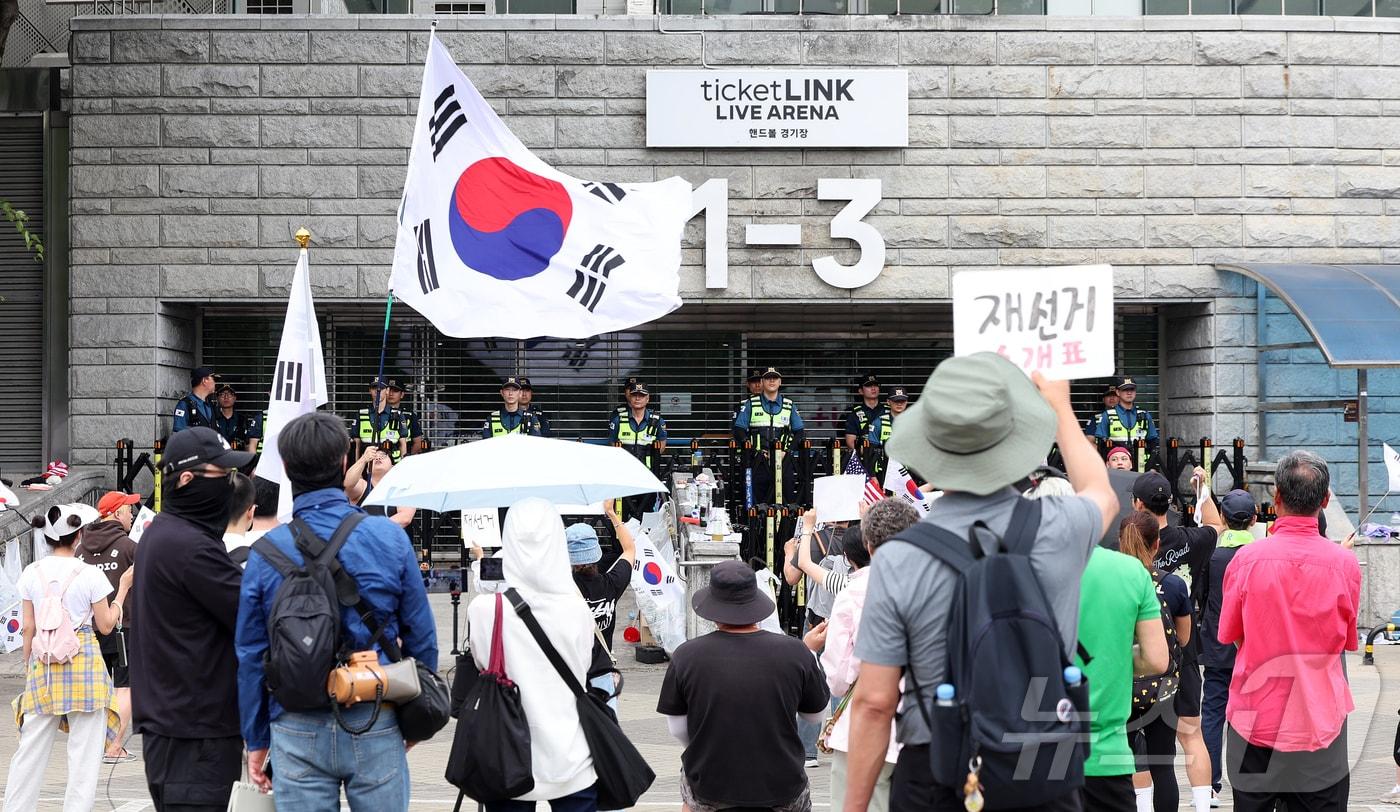 본문 이미지 - 제9회 전국동시지방선거 투표용지 부족 사태를 규탄하며 재선거를 요구하는 집회가 계속되고 있는 8일 서울 송파구 올림픽공원 핸드볼경기장 개표소 앞에 모여 재선거를 요구하는 구호를 외치고 있다. 2026.6.8 ⓒ 뉴스1 김진환 기자