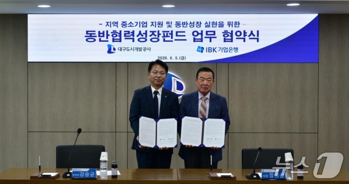 본문 이미지 - 정명섭 대구도시개발공사 사장(오른쪽)과 강승균 IBK기업은행 대구경북동부지역본부장이 중소기업 지원을 위한 동반협력성장펀드 업무협약을 체결한 뒤 협약서를 펼쳐 보이고 있다.(대구도시개발공사 제공, 재판매 및 DB 금지)