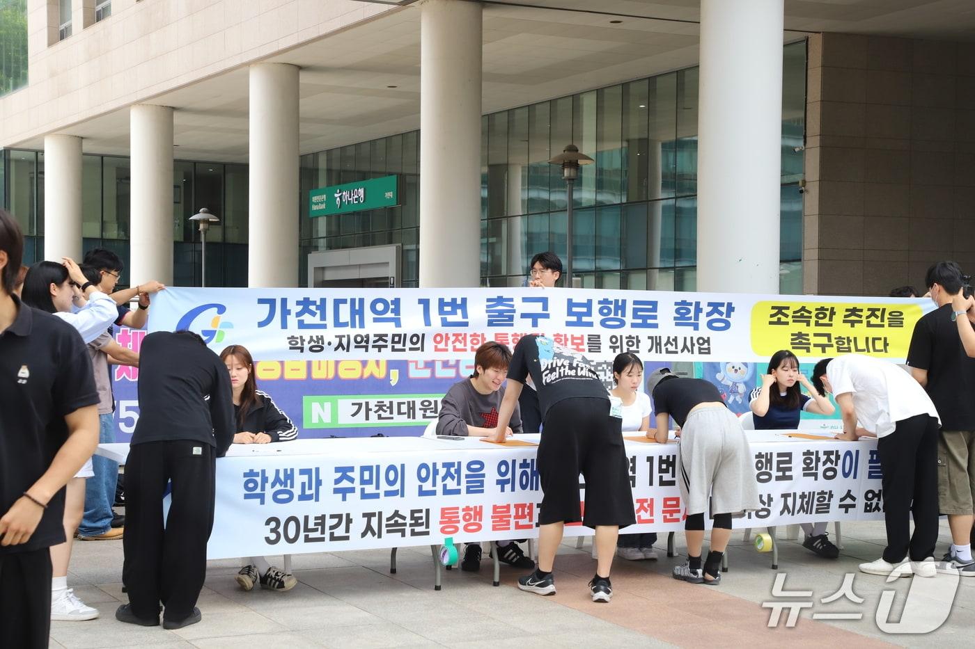 본문 이미지 - 8일 가천대학교 학생들이 대학 비전타워 앞에서 가천대역 1번 출입구 보행로 확장과 안전한 통학환경 조성을 촉구하는 탄원서 서명운동에 참여하고 있다.(가천대 제공. 재판매 및 DB금지)/뉴스1