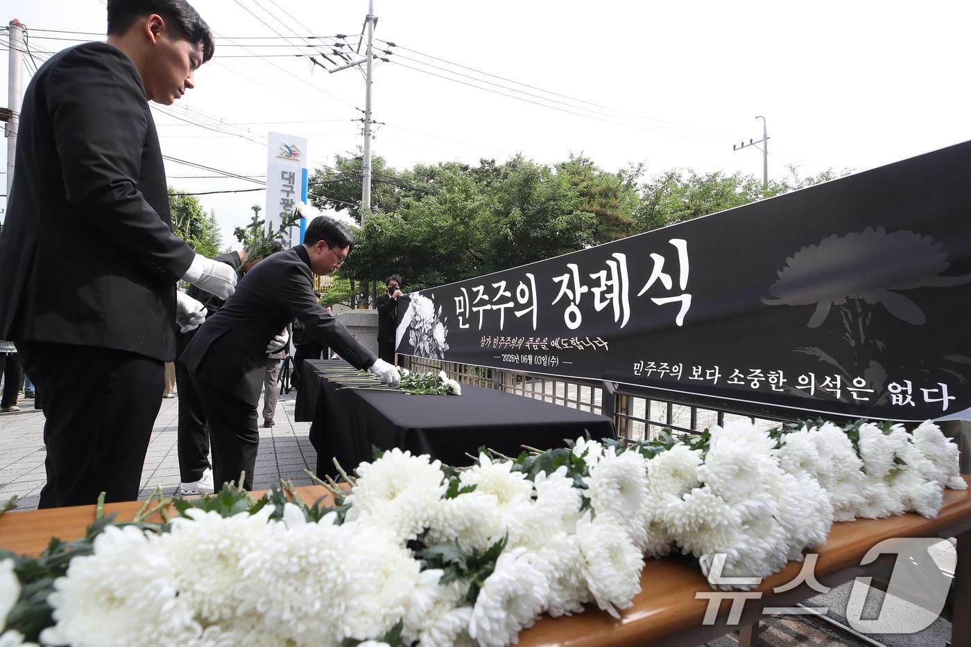 본문 이미지 - 국민의힘 소속으로 6·3 지방선거에 출마해 대구 수성구의원에 당선된 김경민·박새롬 구의원과 시민들이 8일 오후 대구시 선거관리위원회 앞에서 투표용지 부족 사태 등 선거관리 부실에 대한 진상규명과 선관위 책임자 엄중 조사·처벌, 재선거 등을 주장하며 민주주의 장례식을 열고 있다. 2026.6.8 ⓒ 뉴스1 공정식 기자