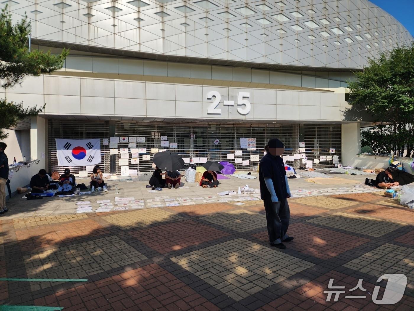 본문 이미지 - 9일 서울시 송파구 올림픽공원 핸드볼경기장의 한 출구 앞에 재선거를 요구하는 시위자들이 돗자리를 펴고 앉아 있다. 이들은 내부에 있는 투표함 반출을 막기 위해 밤샘 농성 중이다. 2026.06.09/ⓒ 뉴스1 권진영 기자
