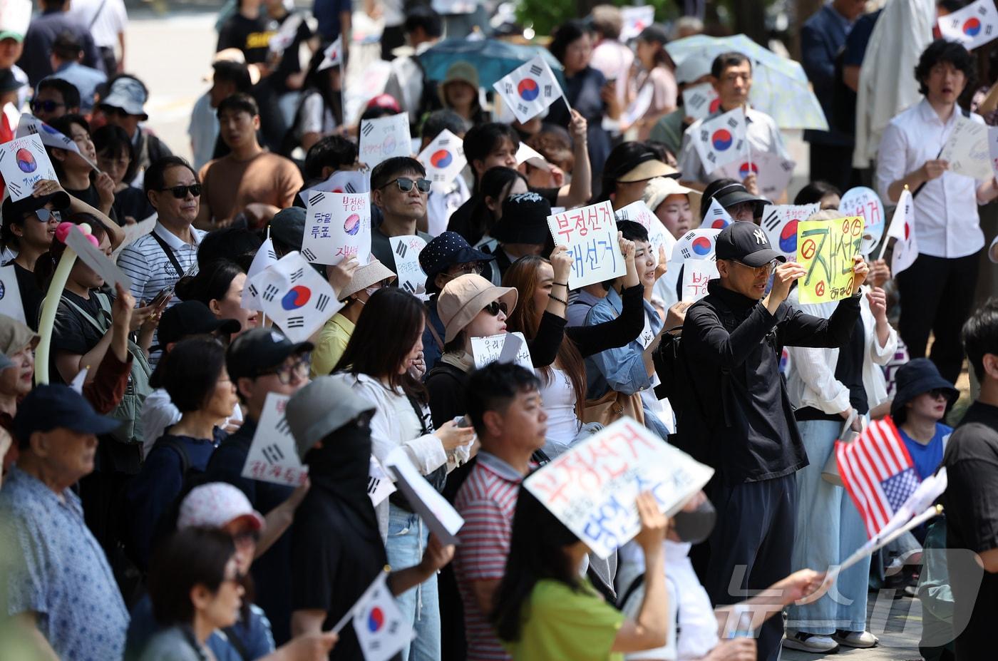 본문 이미지 - 제9회 전국동시지방선거 투표용지 부족 사태에 반발한 시민들이 9일 서울 송파구 올림픽공원 핸드볼경기장에 설치된 개표소 앞에서 재선거를 촉구하며 구호를 외치고 있다. 2026.6.9 ⓒ 뉴스1 김성진 기자