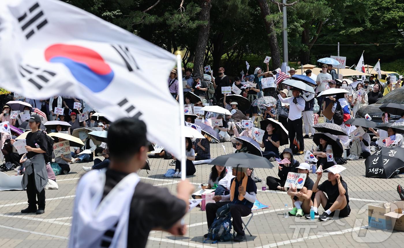 본문 이미지 - 제9회 전국동시지방선거 투표용지 부족 사태에 반발한 시민들이 9일 서울 송파구 올림픽공원 핸드볼경기장에 설치된 개표소 앞에서 재선거를 촉구하며 구호를 외치고 있다. 2026.6.9 ⓒ 뉴스1 김성진 기자