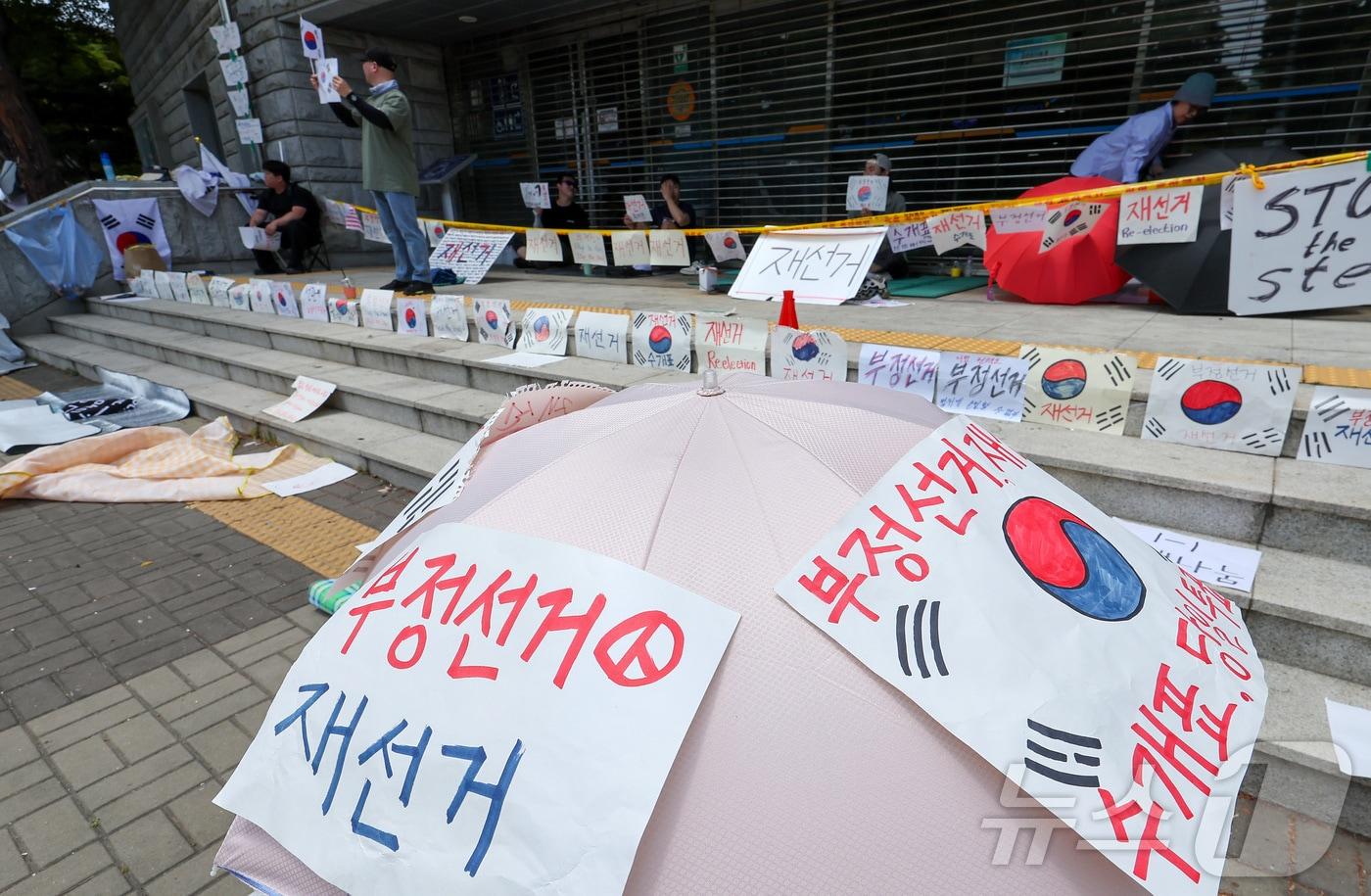 본문 이미지 - 제9회 전국동시지방선거 투표용지 부족 사태에 반발한 시민들이 9일 서울 송파구 올림픽공원 핸드볼경기장에 설치된 개표소 앞에서 재선거를 촉구하며 구호를 외치고 있다. 2026.6.9 ⓒ 뉴스1 김성진 기자