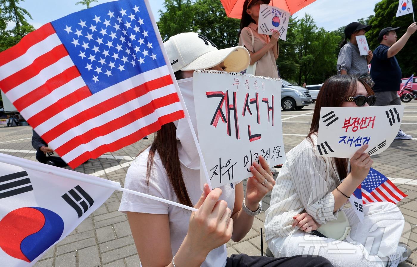 본문 이미지 - 제9회 전국동시지방선거 투표용지 부족 사태에 반발한 시민들이 9일 서울 송파구 올림픽공원 핸드볼경기장에 설치된 개표소 앞에서 재선거를 촉구하며 구호를 외치고 있다. 2026.6.9 ⓒ 뉴스1 김성진 기자