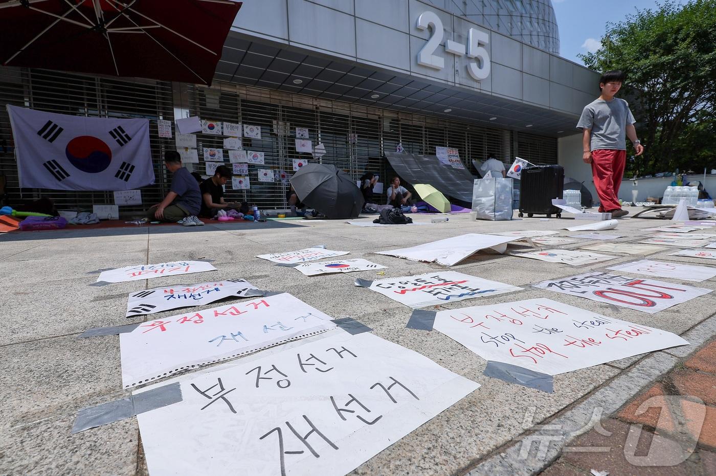 본문 이미지 - 제9회 전국동시지방선거 투표용지 부족 사태에 반발한 시민들이 9일 서울 송파구 올림픽공원 핸드볼경기장에 설치된 개표소 앞에 앉아 있다. 2026.6.9 ⓒ 뉴스1 김성진 기자