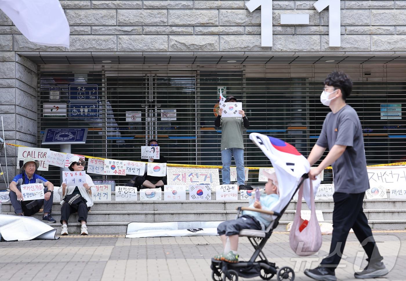 본문 이미지 - 제9회 전국동시지방선거 투표용지 부족 사태에 반발한 시민들이 9일 서울 송파구 올림픽공원 핸드볼경기장에 설치된 개표소 앞에서 재선거를 촉구하며 구호를 외치고 있다. 2026.6.9 ⓒ 뉴스1 김성진 기자