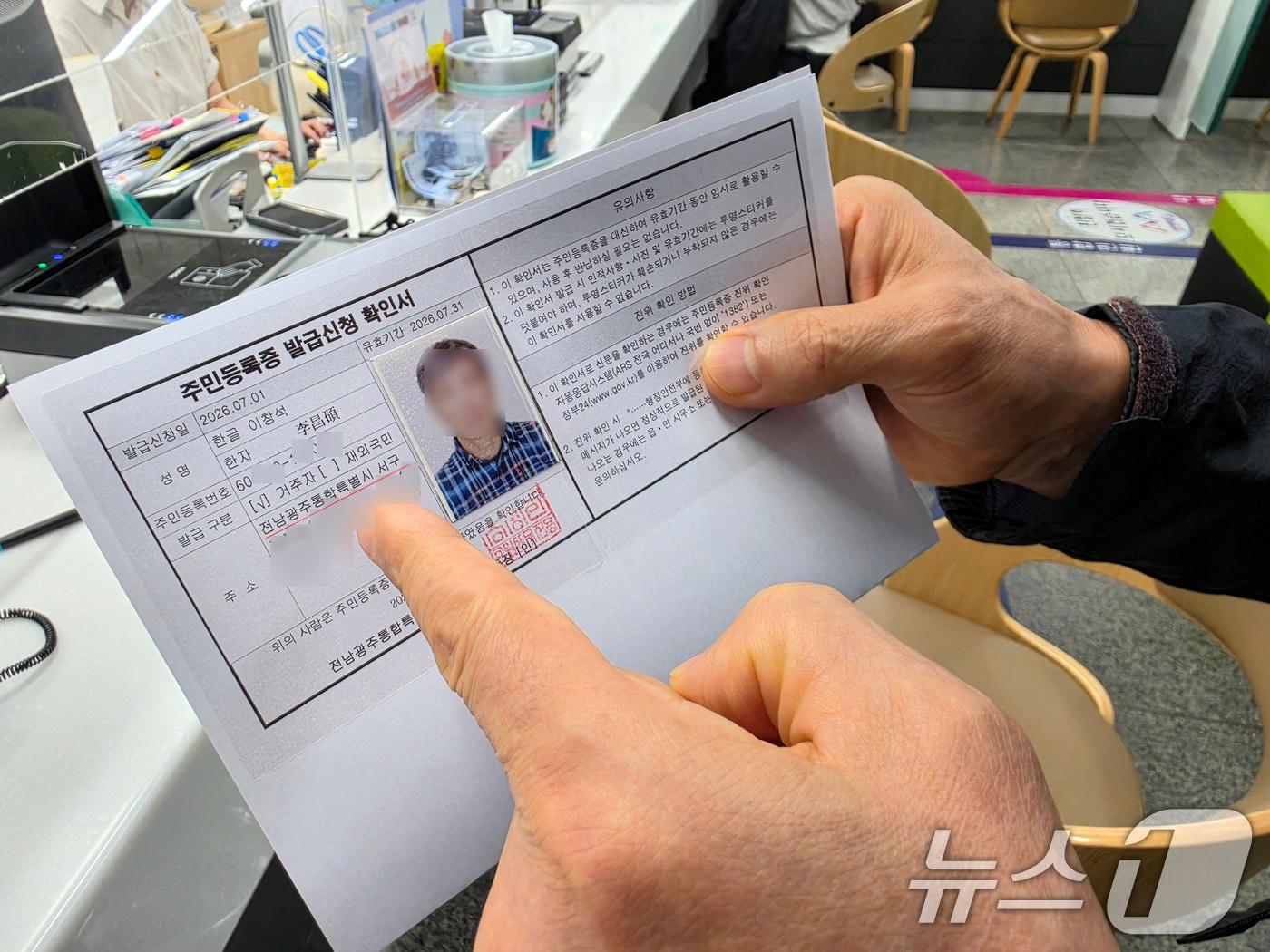 본문 이미지 - 전남광주통합특별시가 출범한 1일 오전 9시 전남광주 서구 금호1동 행정복지센터에서 '1호 주민등록증 발급자'인 이창석 씨(66)가 주민등록증 발급신청 확인서에서 주소를 확인하고 있다.2026.7.1 ⓒ 뉴스1 이수민 기자