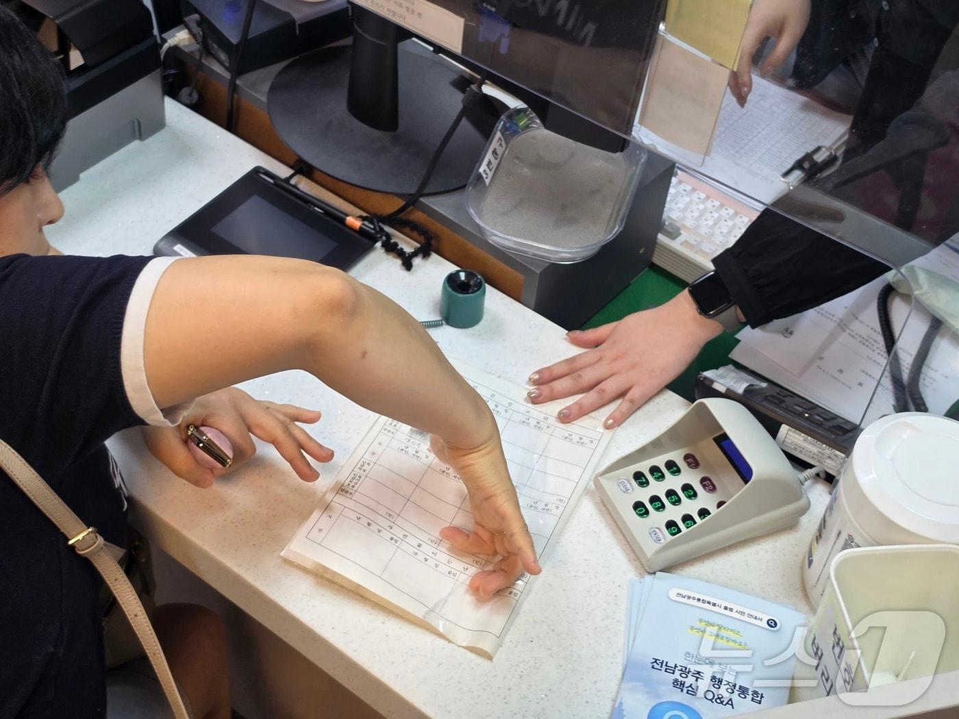 본문 이미지 - 전남광주통합특별시가 출범한 1일 오전 9시 전남광주 서구 치평동 행정복지센터에서 전남광주통합특별시 주민등록증 발급자인 김 모 씨(50)가 신분증 발급을 위해 지문 확인을 하고 있다 2026.7.1 ⓒ 뉴스1 조수민 수습기자