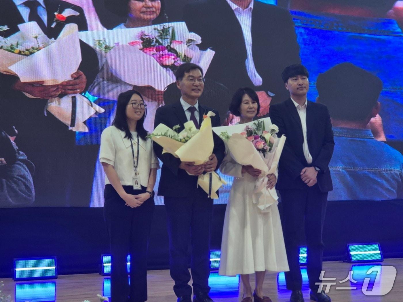 본문 이미지 - 김중남 강원 강릉시장(사진 가운데)이 1일 오전 주문진실내체육관에서 열린 민선 9기 시장 취임식에서 배우자 이순덕 씨와 함께 시청 직원이 전달한 꽃다발을 들고 기념촬영을 하고 있다. 2026.7.1/뉴스1 윤왕근 기자