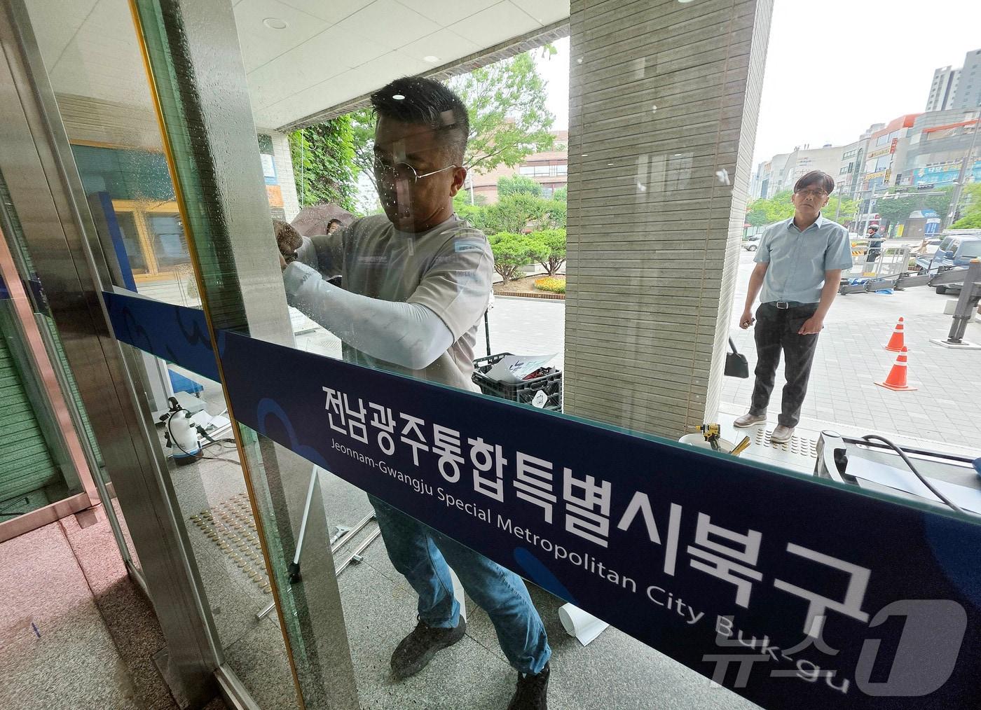 본문 이미지 - 전남광주통합특별시가 출범한 1일 북구청 로비에서 공공청사과 관계자들이 기존 '광주광역시 북구'를 변경된 '전남광주통합특별시 북구'로 교체작업을 하고 있다.(광주 북구 제공. 재판매 및 DB 금지) 2026.7.1 ⓒ 뉴스1