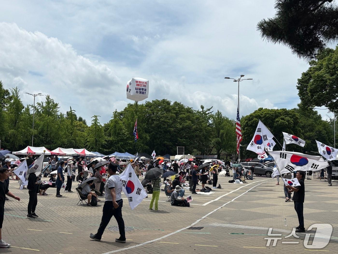 본문 이미지 - 11일 오후 서울 송파구 올림픽공원 일대에서 열린 개표소 봉쇄 시위에서 참가자들이 폭염 속 집회를 이어가고 있다. 2026.7.11 ⓒ 뉴스1 소봄이 기자