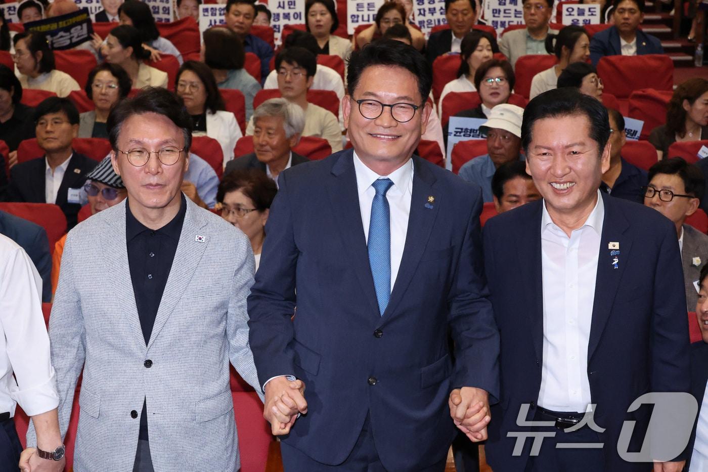 본문 이미지 - 김민석(왼쪽부터)·송영길·정청래 더불어민주당 당대표 후보가 12일 서울 여의도 국회 의원회관에서 열린 전국자치분권민주지도자회의 당대표 후보 정견 발표에서 손을 잡고 기념 촬영하고 있다. 2026.7.12 ⓒ 뉴스1 신웅수 기자
