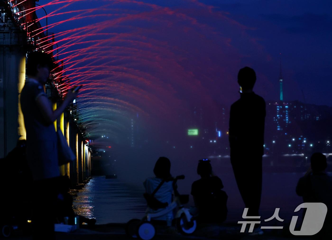 본문 이미지 - 전국 대부분 지역에 폭염특보가 이어지며 낮 최고기온이 37도까지 오르는 찜통더위가 이어진 12일 오후 서울 서초구 신반포로 반포한강공원을 찾은 시민들이 시원한 물줄기를 내뿜는 반포대교 달빛무지개분수를 바라보며 더위를 식히고 있다. 2026.7.12 ⓒ 뉴스1 박정호 기자