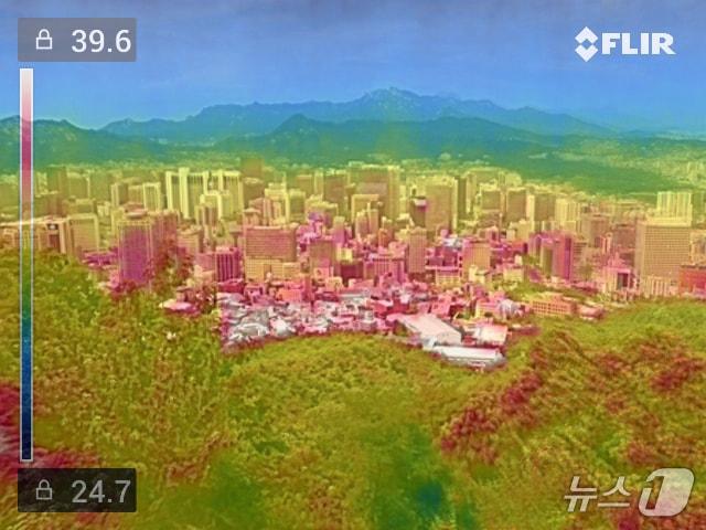 본문 이미지 - 전국 대부분의 지역에 폭염특보가 내려진 13일 남산에서 내려다본 서울 도심을 열화상 카메라로 촬영해 실물사진과 레이어 합성했다. 남산 숲의 나무는 상대적으로 온도가 낮아 초록색으로 나타난 반면 도심의 건물들은 온도가 높아 붉은색으로 나타났다. 2026.7.13 ⓒ 뉴스1 구윤성 기자