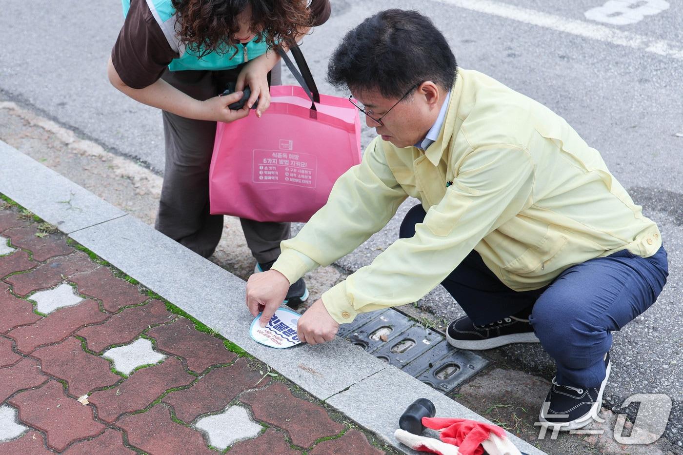 본문 이미지 - 한대희 경기 군포시장이 '빗물받이 위치 스티커'를 부착하고 있는 모습. (군포시 제공. 재판매 및 DB 금지) 2026.7.13/뉴스1
