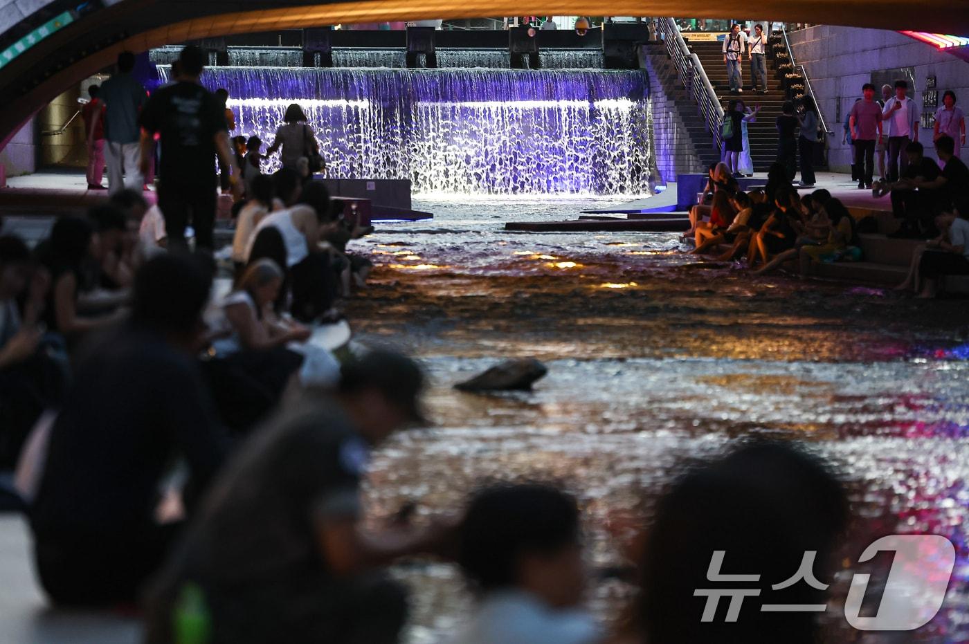 본문 이미지 - 서울 전역에 열대야주의보가 발효된 13일 저녁 서울 청계천을 찾은 관광객과 시민들이 더위를 식히고 있다. 2026.7.13 ⓒ 뉴스1 김도우 기자
