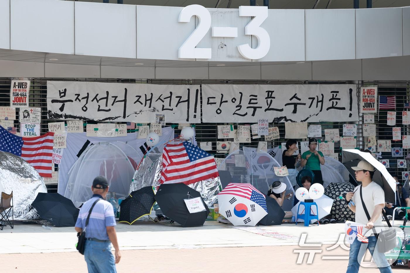 본문 이미지 - 6·3지방선거 이후 한 달 넘게 개표소 봉쇄 시위가 계속되고 있는 지난 17일 서울 송파구 올림픽공원 핸드볼경기장 입구 앞을 시민들이 지나고 있다. 2026.7.17 ⓒ 뉴스1 안은나 기자