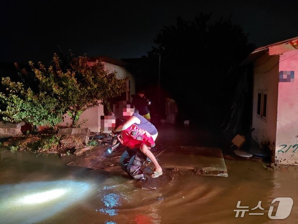 본문 이미지 - 17일 오후 8시 13분쯤 경북 구미시 고아읍 괴평리 한 주택이 폭우로 침수돼 일가족 4명이 고립됐다가 소방관에 의해 60대 여성이 구조되고 있다. (경북소방 제공. 재판매 및 DB금지)) 2026.7.18/뉴스1
