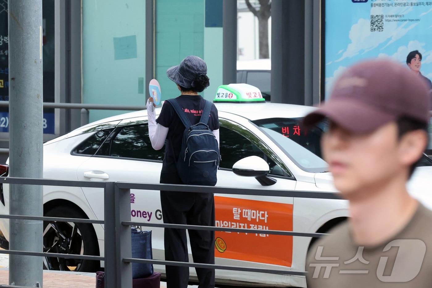 본문 이미지 - 18일 오후 전남광주통합특별시 서구 광천동 광주종합버스터미널 버스정류장에서 시민이 택시를 타려고 부채질 하며 대기하고 있다. 2026.7.18 ⓒ 뉴스1 조수민 기자