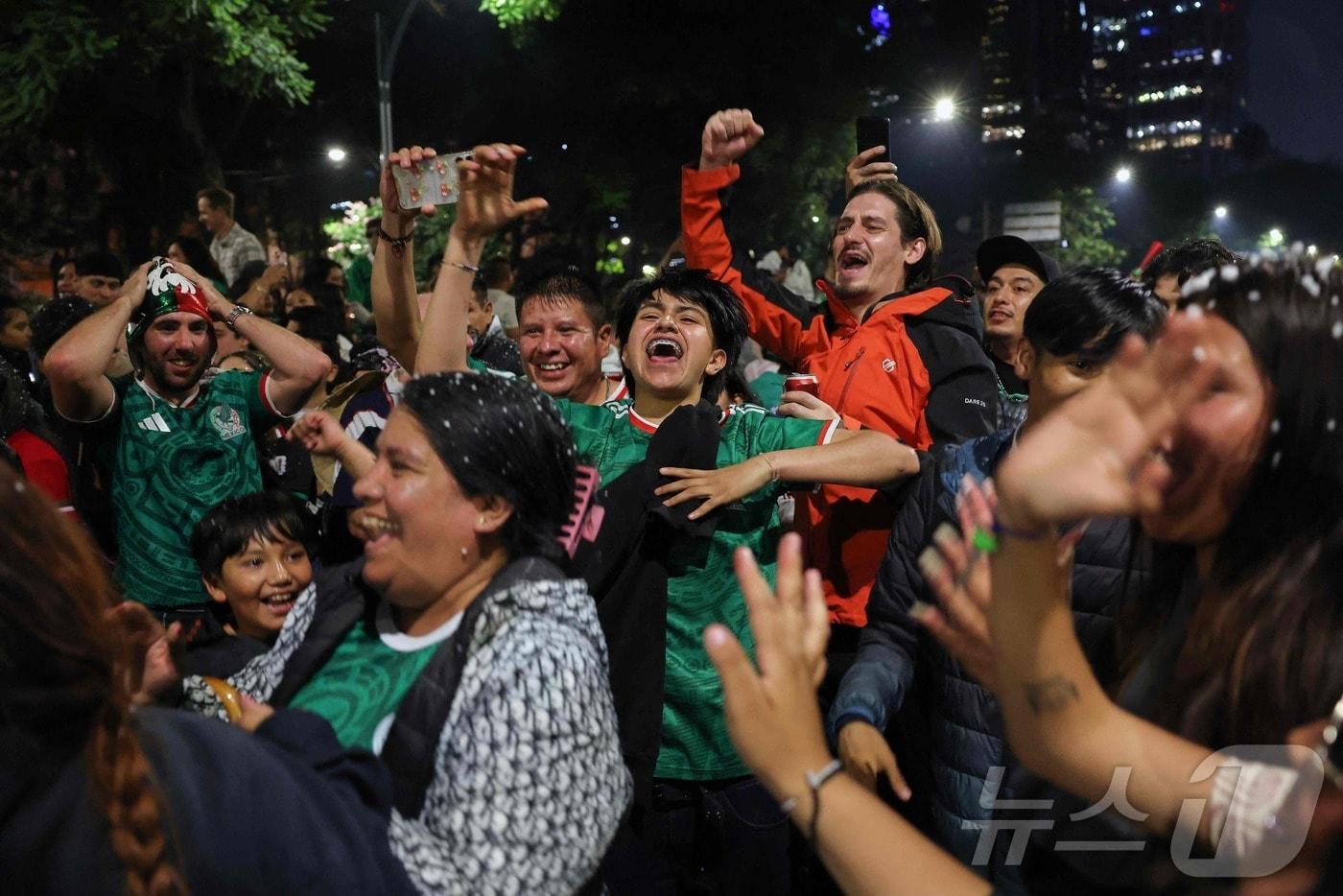 본문 이미지 - 멕시코 축구 팬들이 30일(현지시간) 멕시코시티 독립기념비에서 2026 북중미 월드컵 32강 에콰도르전 승리를 축하하고 있다. 2026.6.30. ⓒ 뉴스1 ⓒ AFP=뉴스1