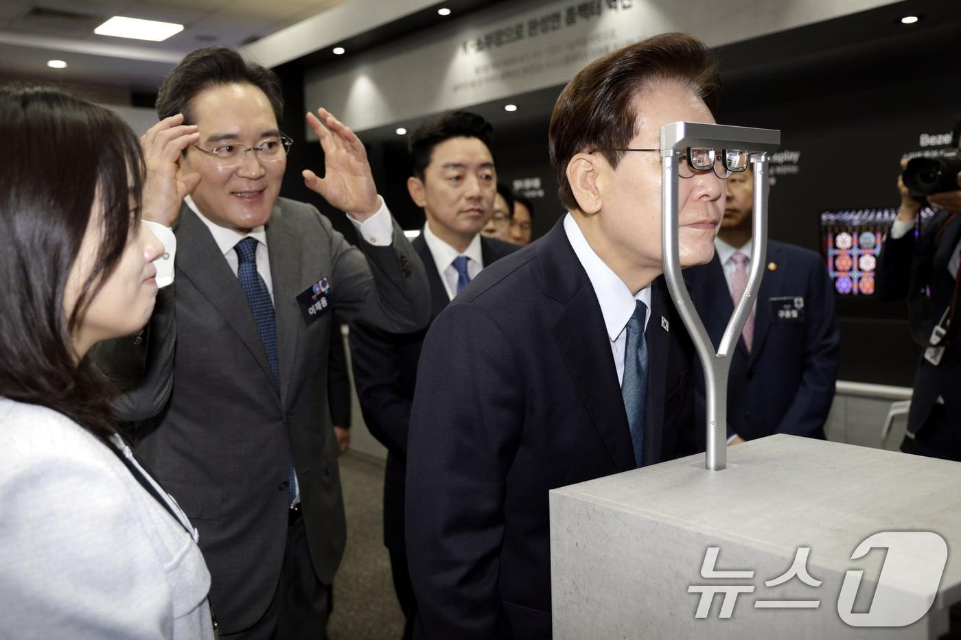 본문 이미지 - 이재명 대통령이 2일 충남 아산에서 열린 충청권 첨단산업 발전비전 국민보고회에서 AR 글라스를 체험하고 있다. 왼쪽은 이재용 삼성전자 회장. 2026.7.2 ⓒ 뉴스1 허경 기자