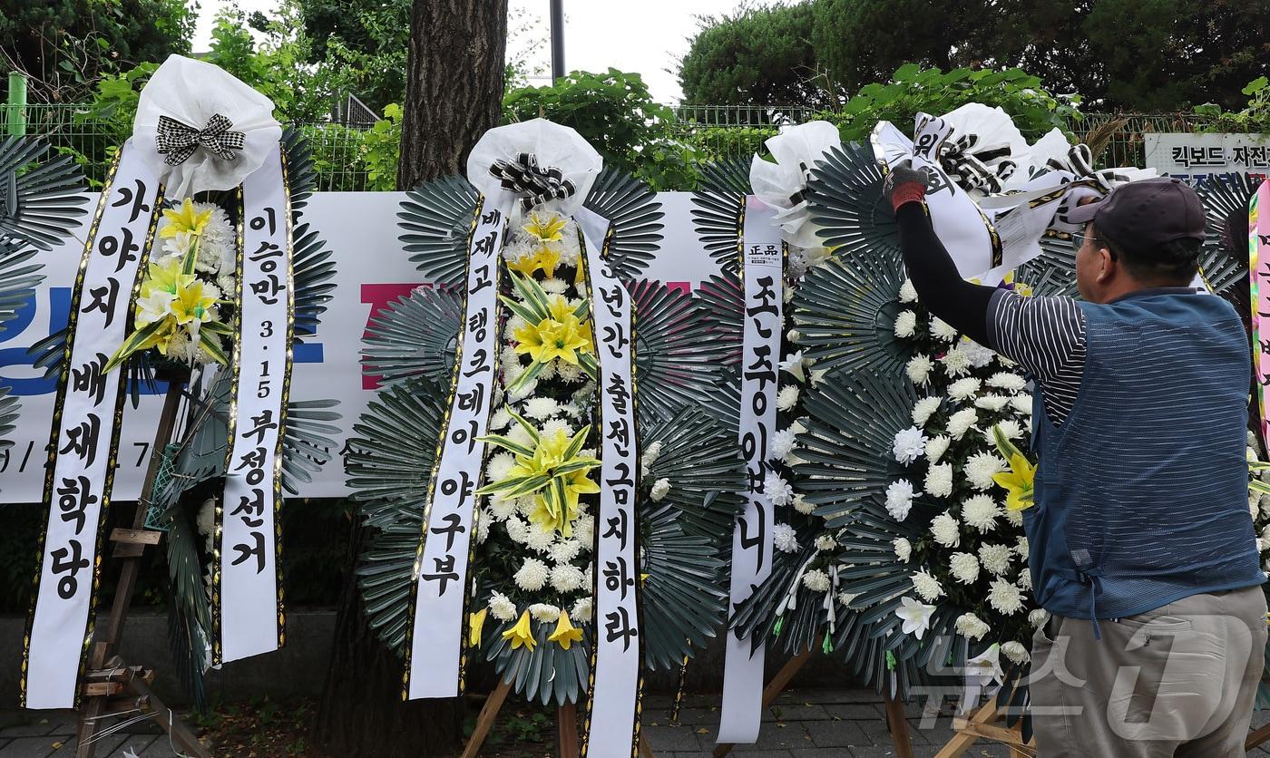 본문 이미지 - 2일 서울 강동구 배재고등학교 앞에 한 관계자가 배재고등학교 야구부를 비판하는 근조화환을 놓고 있다. 앞서 배재고 선수들은 지난달 29일 서울 목동구장에서 열린 제81회 청룡기 전국고교야구선수권대회에서 상대 팀인 광주제일고를 향해 "스타벅스 가야지＂, ＂탱크데이＂ 등의 구호를 외쳐 논란이 됐다. 이에 대한야구소프트볼협회는 전날 스포츠공정위원회를 열고 배재고 야구부에 전국대회 출전 정지 6개월 중징계를 내렸다. 2026.7.2 ⓒ 뉴스1 김성진 기자