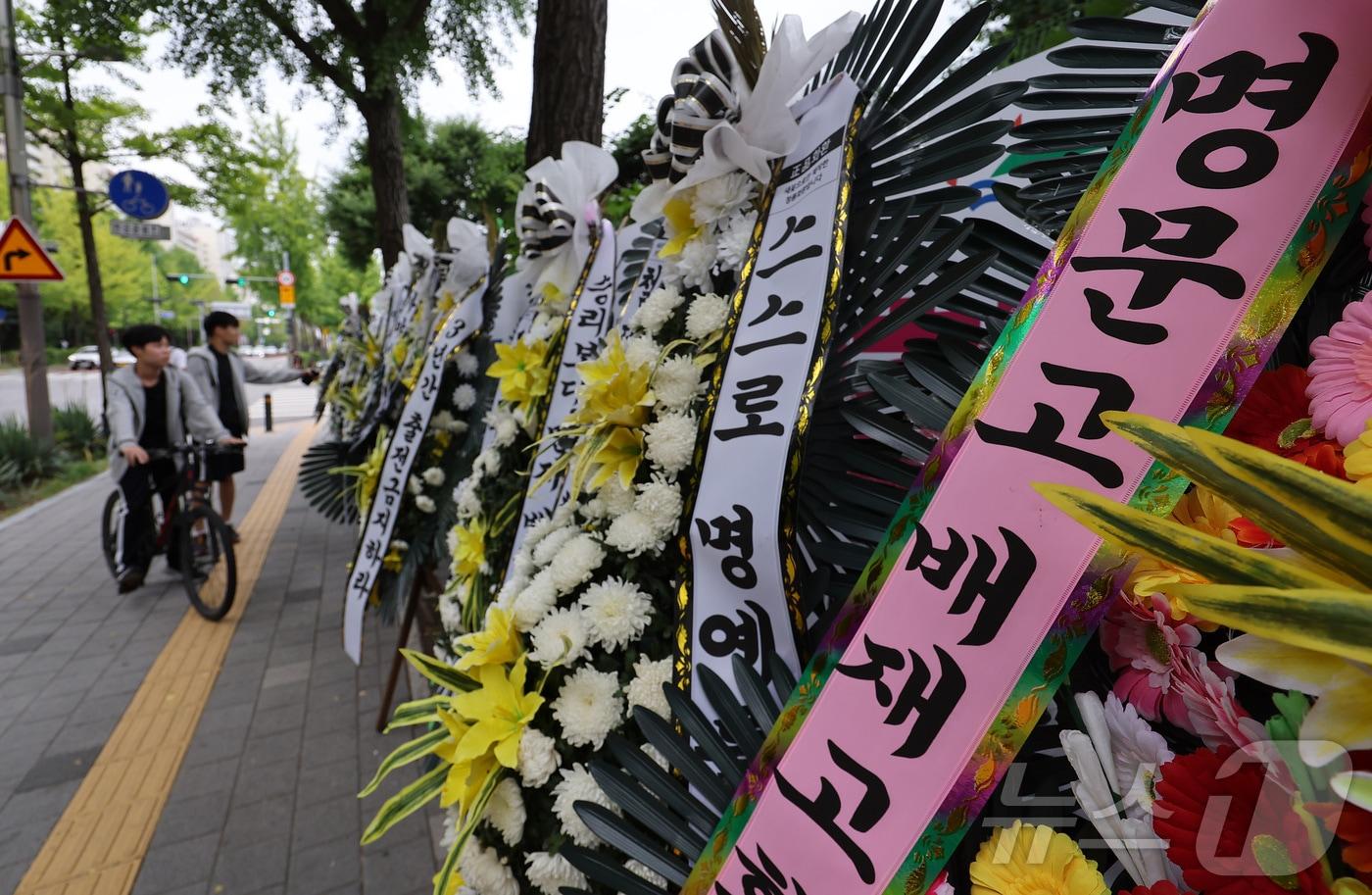 본문 이미지 - 2일 서울 강동구 배재고등학교 앞에 배재고등학교 야구부를 비판하는 근조화환과 응원하는 화환이 놓여 있다.  2026.7.2 ⓒ 뉴스1 김성진 기자