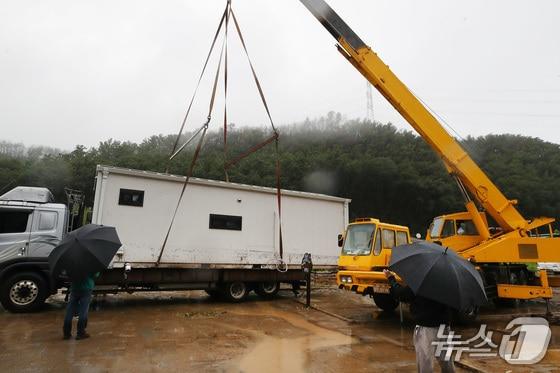 본문 이미지 - 19일 경북 안동시 일직면 귀미리 산불 이재민 주거용 임시 주택 일대가 집중호우로 침수된 가운데 수해 복구 현장에 다시 폭우가 쏟아지자 크레인과 트럭을 동원해 주택을 인근 폐교로 옮기고 있다. 2026.7.19 ⓒ 뉴스1 공정식 기자