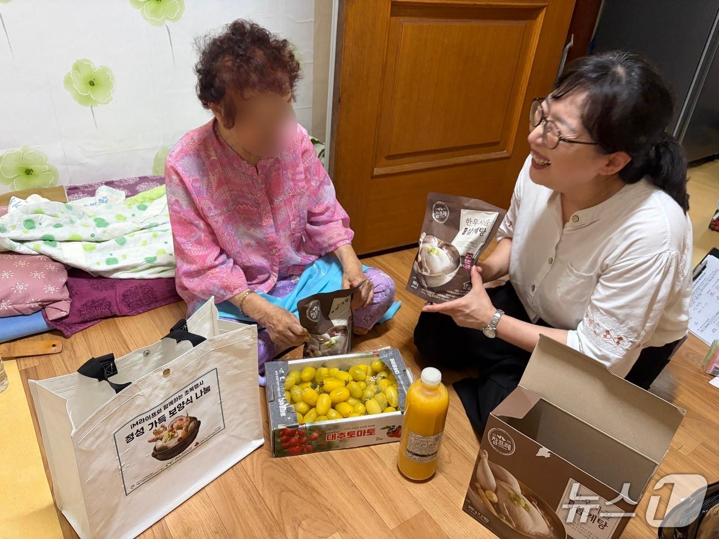 본문 이미지 - 서울시성북구재가노인복지기관 관계자가 지난 15일 재가 어르신 가정을 방문해 초복 맞이 보양식과 제철 과일, 건강 음료를 전달하고 있다/사진제공=iM라이프