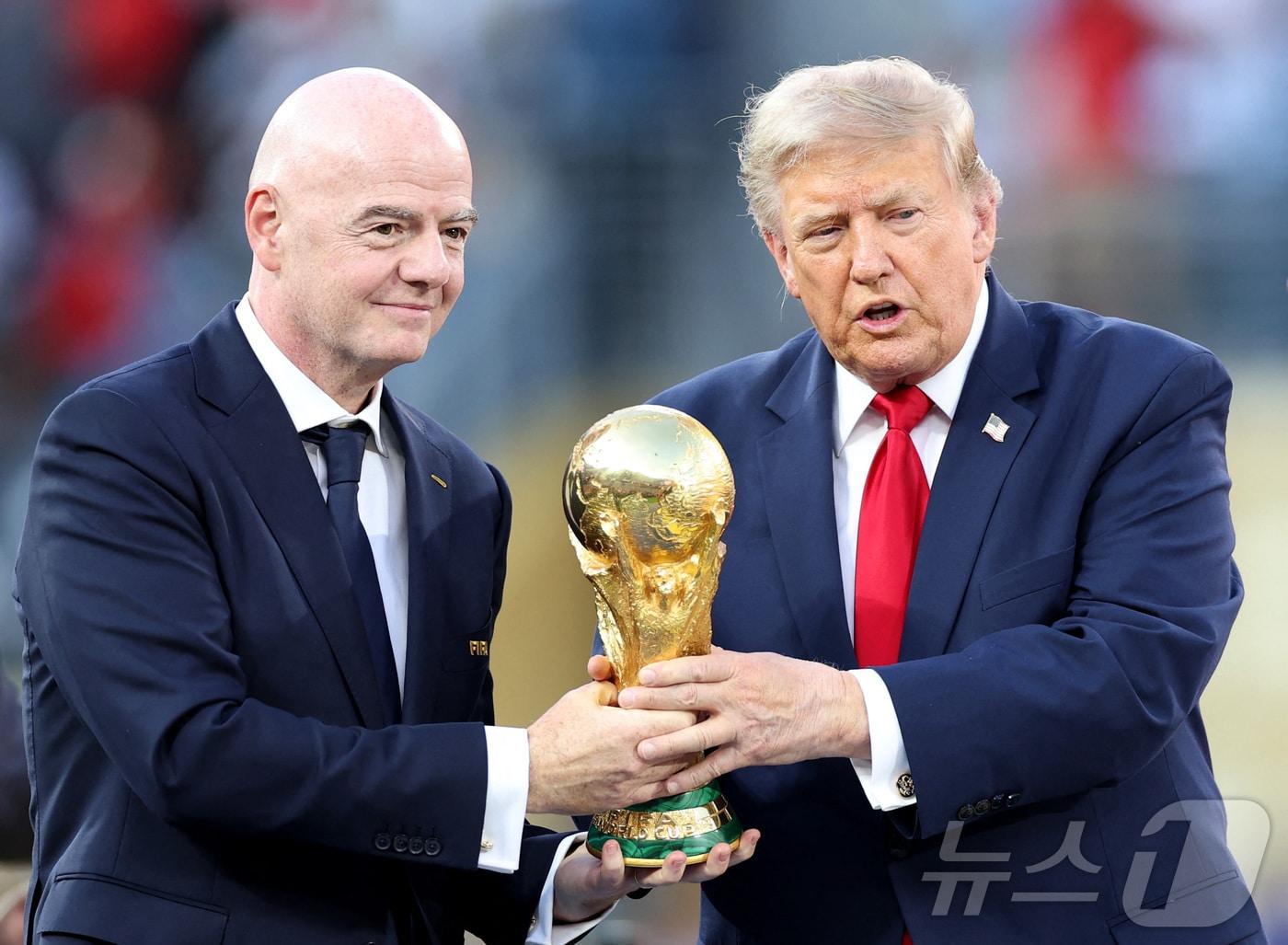 본문 이미지 - 도널드 트럼프 미국 대통령과 잔니 인판티노 국제축구연맹(FIFA·피파) 회장이 지난 19일(현지시간) 미국 뉴저지주 이스트러더퍼드의 뉴욕 뉴저지 스타디움에서 열린 2026 FIFA 월드컵 스페인과 아르헨티나의 결승전 경기 직후 열린 시상식에서 스페인의 주장 로드리(16번)에게 전달하기 전 월드컵 우승 트로피를 들어 올리고 있다. 2026.07.19. ⓒ AFP=뉴스1  