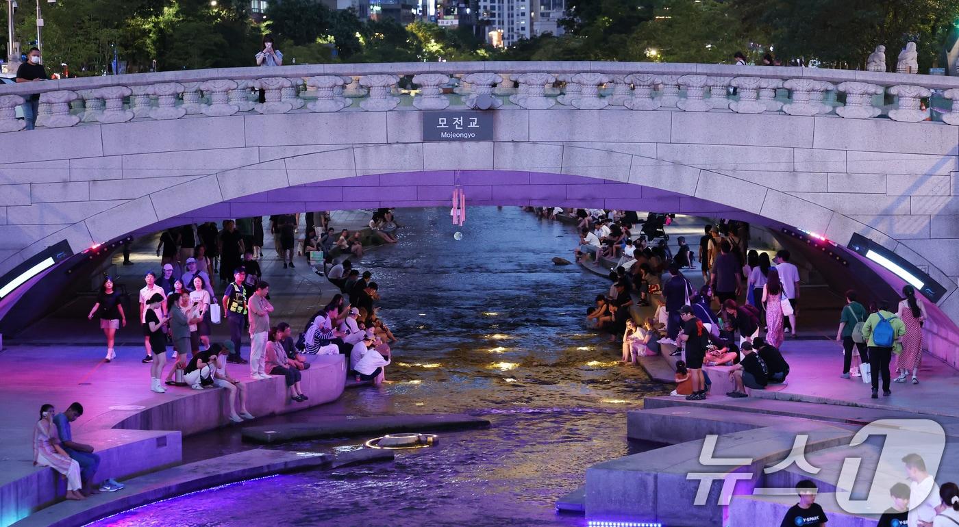 본문 이미지 - 서울 전역에 폭염주의보와 열대야주의보가 동시 발효된 26일 저녁 서울 중구 청계천을 찾은 관광객과 시민들이 물가에 앉아 더위를 식히고 있다. 2026.7.26 ⓒ 뉴스1 오대일 기자