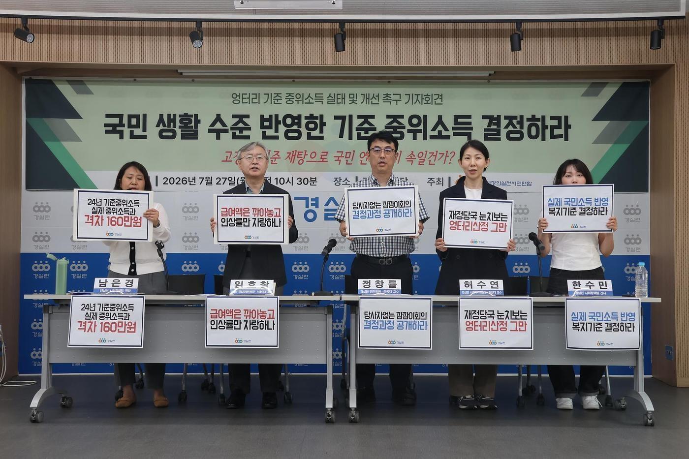 본문 이미지 - 27일 서울 종로구 경제정의실천시민연합 강당에서 열린 '엉터리 기준 중위소득 실태 및 개선 촉구 기자회견'에서 참석자들이 실제 국민 생활 수준을 반영한 기준 중위소득 산정체계 마련을 촉구하는 손팻말을 들고 있다. 2026.7.27 (경실련 제공)