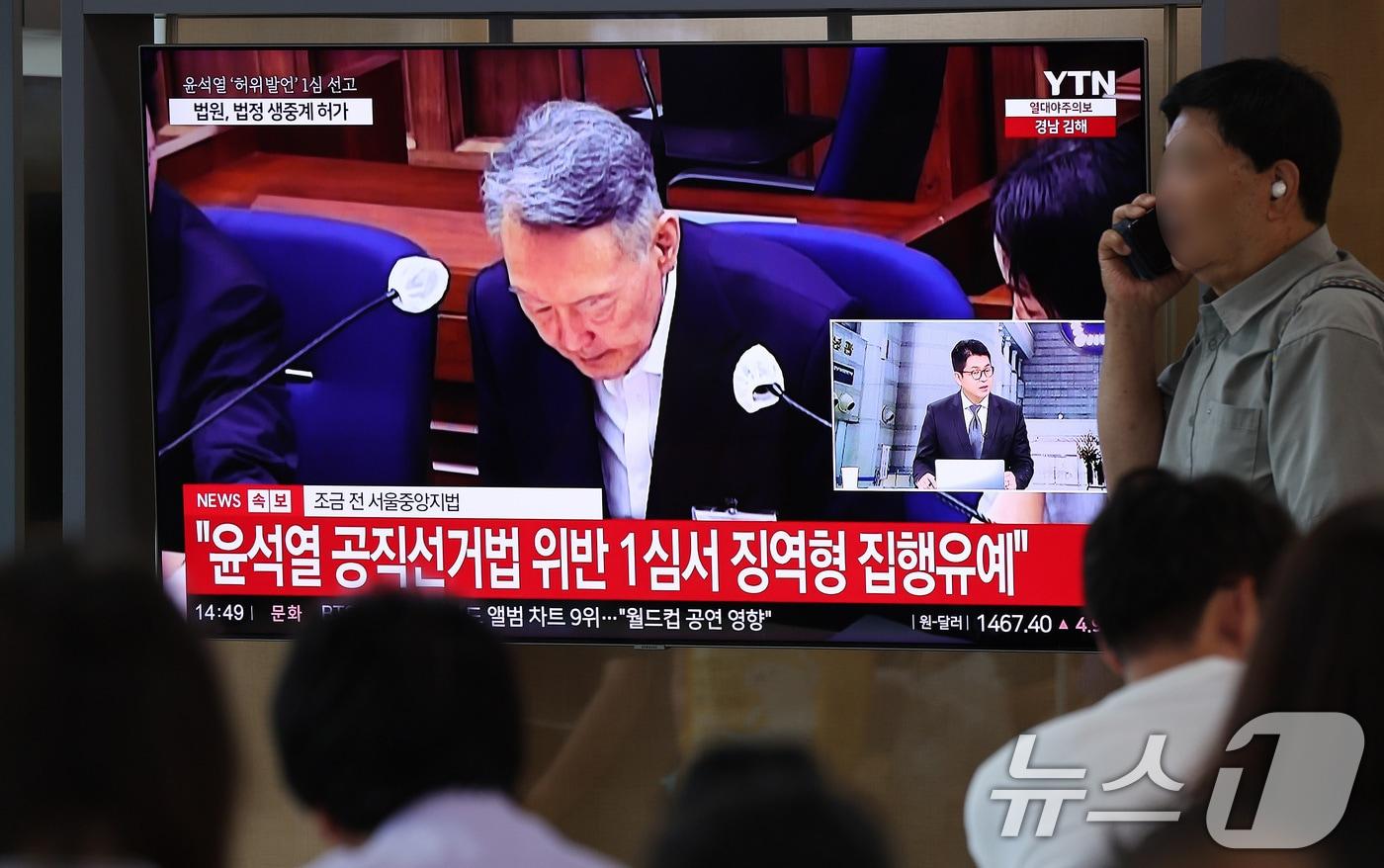 본문 이미지 - 27일 서울 용산구 서울역 대합실에서 시민들이 윤석열 전 대통령의 공직선거법 위반 혐의 1심 선고 생중계를 바라보고 있다. 이날 법원은 윤석열에게 징역 1년 6개월에 집행유예 3년을 선고했다. 2026.7.27 ⓒ 뉴스1 박지혜 기자
