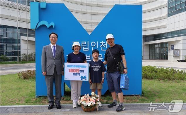 본문 이미지 - 우동식 국립인천해양박물관 관장이 100만번째 관람객에게 축하 꽃다발과 선물을 전달하고, 기념 촬영을 하고 있다.(국립인천해양박물관 제공)