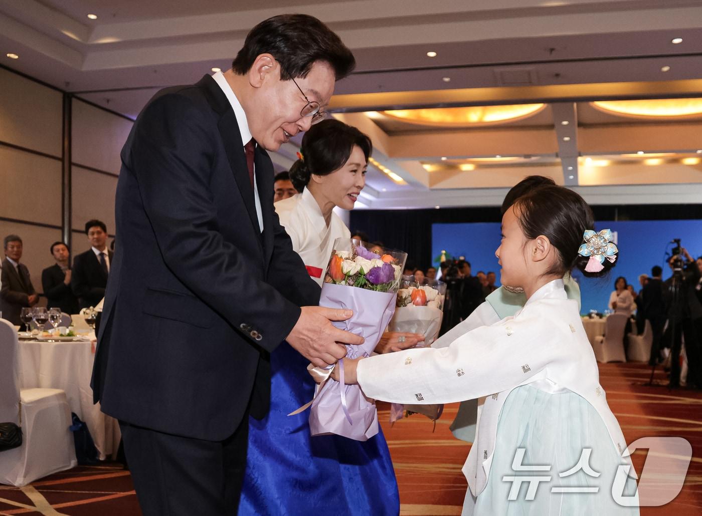 본문 이미지 - 이재명 대통령과 김혜경 여사가 29일(현지시간) 칠레 산티아고 한 호텔에서 열린 동포 만찬간담회에서 화동들에게 꽃다발을 전달 받고 있다. 2026.7.30 ⓒ 뉴스1 허경 기자