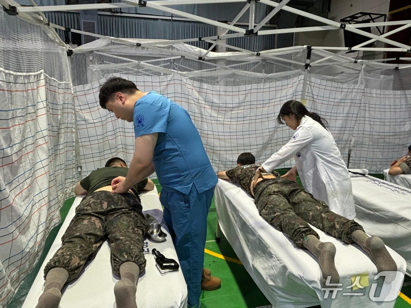 본문 이미지 - 자생한방병원 의료진이 제7기동군단 장병 대상 의료봉사에서 한의통합치료를 하고 있다.(자생의료재단 제공)