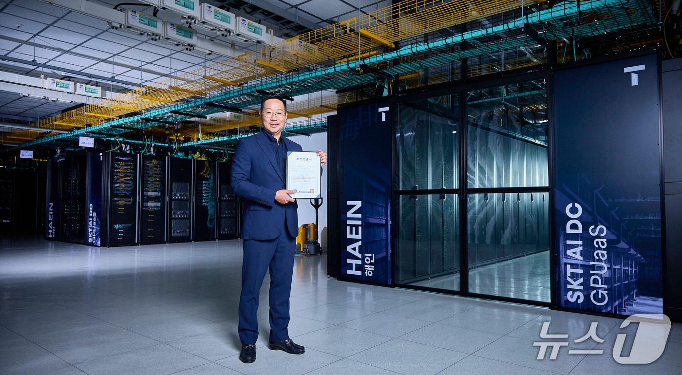 본문 이미지 - 사진은 해인 클러스터 앞에서 김명국 SKT AI Factory 사업담당이 CSAP 인증서를 들고 포즈를 취하는 모습. (SK텔레콤 제공)