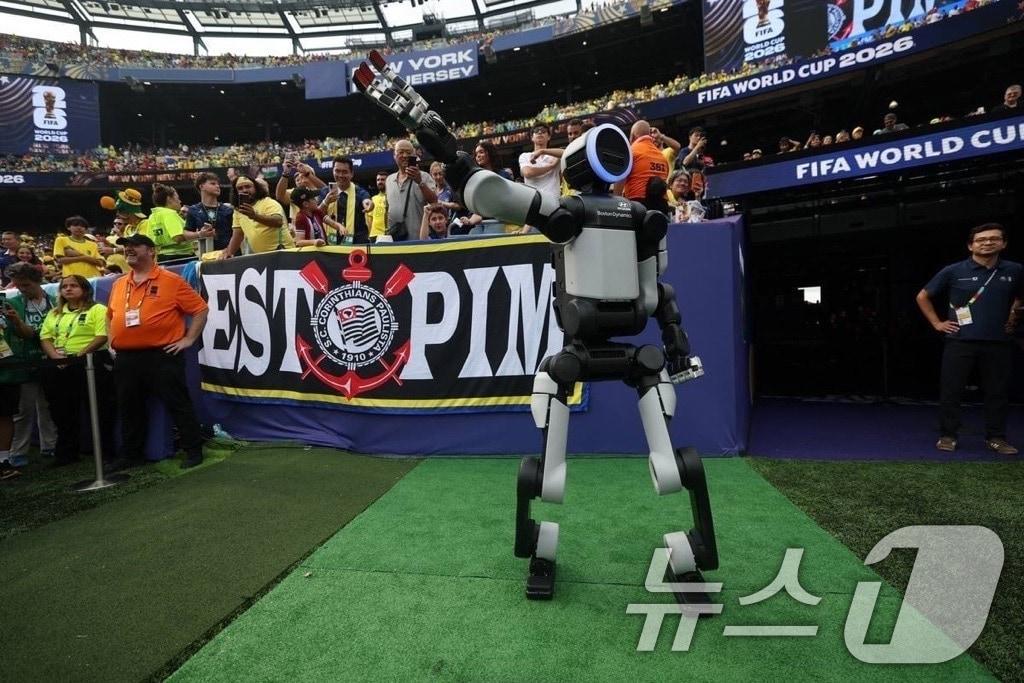 본문 이미지 - 현대자동차는 미국 뉴욕 뉴저지 스타디움에서 열린 '피파 월드컵 2026™' 16강전 하프타임에서 차세대 전동식 휴머노이드 로봇 '아틀라스'가 심판에게 경기구를 전달하는 퍼포먼스를 성공적으로 시연했다고 6일 밝혔다. 아틀라스가 관중을 향해 손을 흔들고 있다. (현대자동차 제공. 재판매 및 DB금지) 2026.7.6 ⓒ 뉴스1