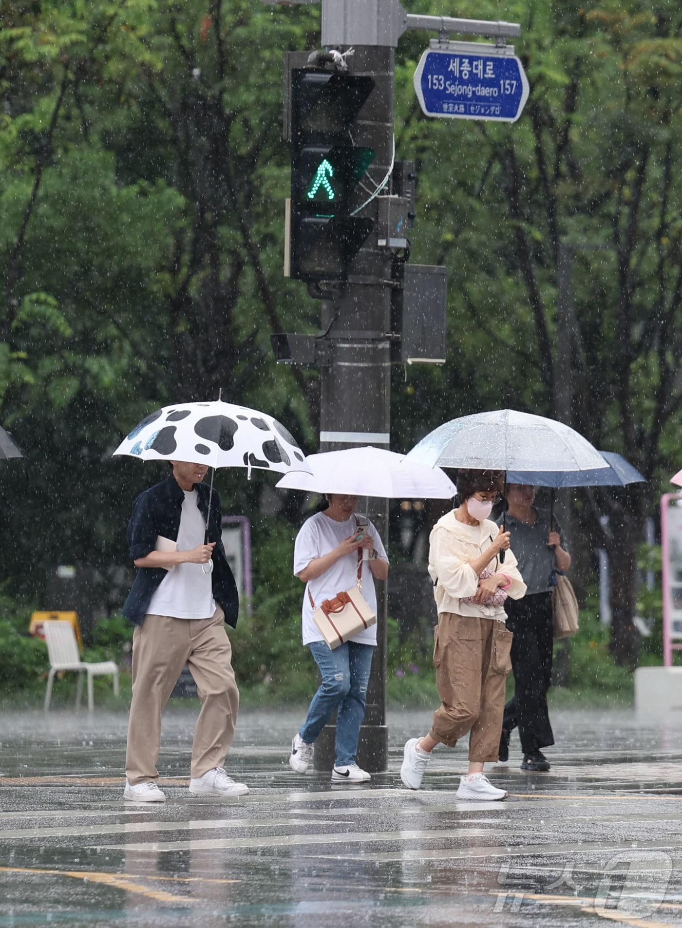 본문 이미지 - 비가 내리고 있는 6일 오전 서울 종로구 세종대로 사거리에서 우산을 쓴 시민들이 이동하고 있다. 2026.7.6 ⓒ 뉴스1 이종수 기자