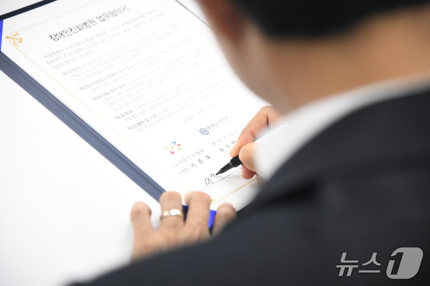 본문 이미지 - 지난 10일 노원구청 소회의실에서 진행된 장애인친화병원 협약식에서 서준오 노원구청장이 서명을 하고 있다