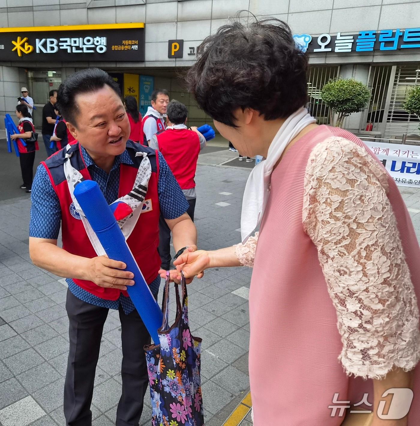 본문 이미지 - 노학양 한국자유총연맹 부산진구지회장(왼쪽)이 12일 부산진구 부전동에서 시민들에게 태극기를 무료로 나눠주고 있다. 2026.8.12/뉴스1 ⓒ News1 임순택 기자