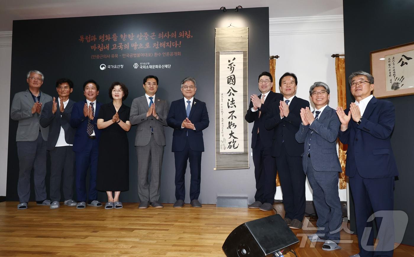 본문 이미지 - 허민 국가유산청장(왼쪽 여섯번째)을 비롯한 참석자들이 13일 오전 서울 중구 덕수궁 중명전에서 열린 안중근 의사 유묵 ‘만국공법불여대포(萬國公法不如大砲)’ 환수 언론공개회에서 기념촬영을 하고 있다. 2026.8.13 ⓒ 뉴스1 김민지 기자