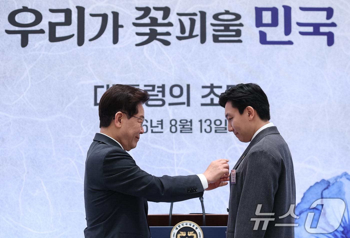 본문 이미지 - 이재명 대통령이 13일 청와대에서 열린 국가유공자 및 보훈 가족 초청 오찬 행사에서 재외 독립유공자 후손 김막심 씨에게 태극기 배지를 증정하고 있다. (청와대통신사진기자단) 2026.8.13 ⓒ 뉴스1 이재명 기자