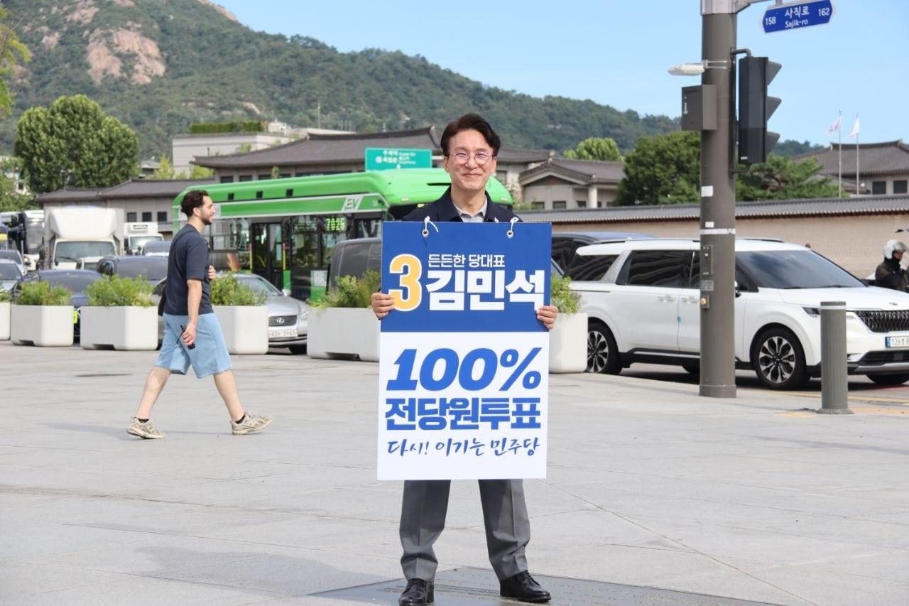 본문 이미지 - 김민석 더불어민주당 당대표 후보가 13일 오전 서울 종로구 정부서울청사 앞에서 출근인사를 하는 모습.(김 후보 SNS)