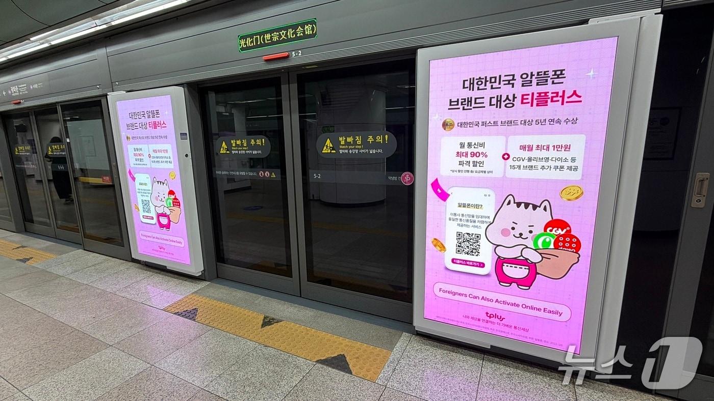 본문 이미지 - 태광그룹 계열사 한국케이블텔레콤(kct)의 알뜰폰 브랜드 티플러스(tplus)가 서울 주요 지하철 역사에서 진행 중인 스크린도어 광고 모습. 티플러스는 외국인 고객 접점을 넓히기 위해 홈페이지 다국어 서비스를 확대하고 서울 14개 역사 100개소에서 한국어·영어 광고를 운영한다. (한국케이블텔레콤 제공)