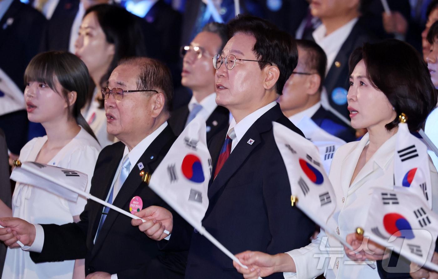 본문 이미지 - 이재명 대통령과 김혜경 여사가 15일 서울 종로구 세종문화회관에서 열린 제81주년 광복절 경축식에서 광복절 노래를 제창하며 태극기를 흔들고 있다. 2026.8.15 ⓒ 뉴스1 이재명 기자