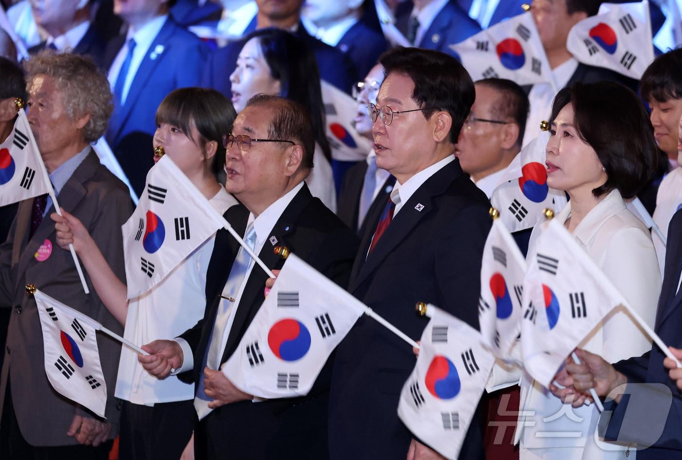 본문 이미지 - 이재명 대통령과 김혜경 여사가 15일 서울 종로구 세종문화회관에서 열린 제81주년 광복절 경축식에서 광복절 노래를 제창하며 태극기를 흔들고 있다. 2026.8.15 ⓒ 뉴스1 이재명 기자