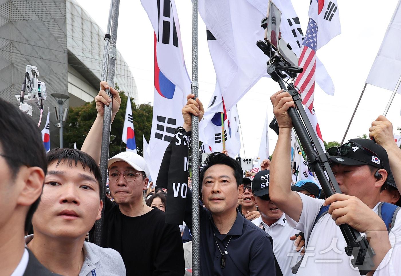 본문 이미지 - 장동혁 국민의힘 대표가 광복절인 15일 서울 송파구 올림픽공원 핸드볼경기장에서 열린 투표 용지 부족 사태 관련 참정권 수호 집회에 태극기를 들고 참석하고 있다. 2026.8.15 ⓒ 뉴스1 김성진 기자